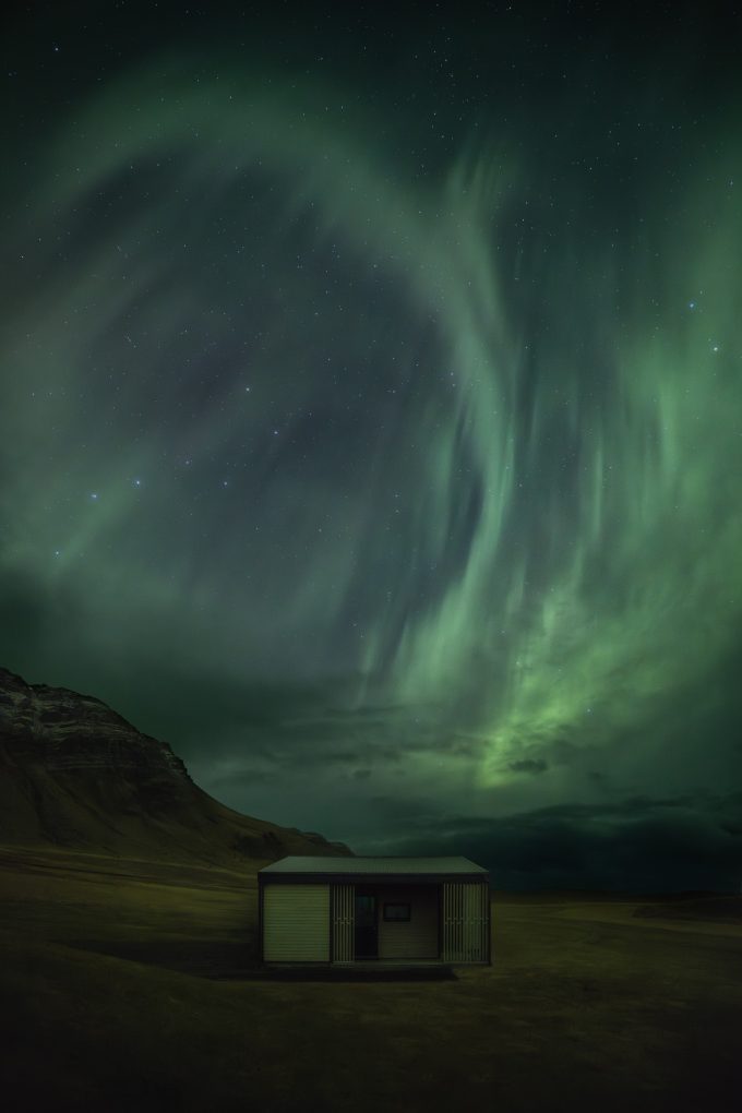 Aurora über einer Hütte auf Island mit dem Sternbild „Großer Wagen“